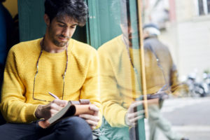 man writing in notebook